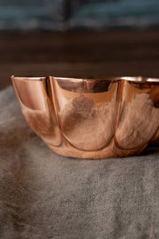 Coppermill Kitchen LLC - Vintage Inspired Copper Fluted Bowl with Crown Engraving, displayed on linen cloth, showcasing its elegant fluted design and embossed crown emblem.