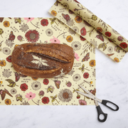Bee's Wrap - Cut-to-Size Roll - Meadow Magic, showcasing a crusty bread loaf on floral-patterned, reusable vegan wrap, with scissors on a marble-like surface.