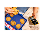 Hand holding Great Jones | Little Sheet - Pepper with a freshly baked cookie, showcasing its nonstick surface, ideal for small batch baking.