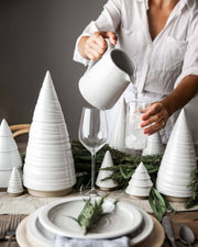 Farmhouse Pottery - Spruce Woodland Trees: Petite, featured on a minimalist holiday table with ceramic plates, greenery, and ice-filled glass, enhancing the elegant decor.