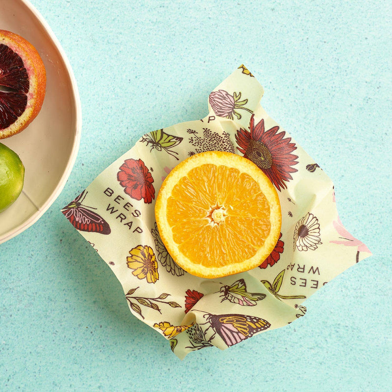 Bee's Wrap - Assorted 3 Pack - Meadow Magic, Plant Based Wax: floral-patterned wrap with halved orange, bowl with citrus fruits. Sustainable, reusable kitchen essential from Athens Cooks.