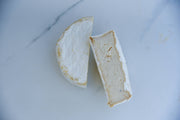 Rebel Cheese - Cave-Aged Truffle Brie Plant Based, 5.4 oz, on marble surface; features a white crust, showcasing its artisanal, creamy texture.
