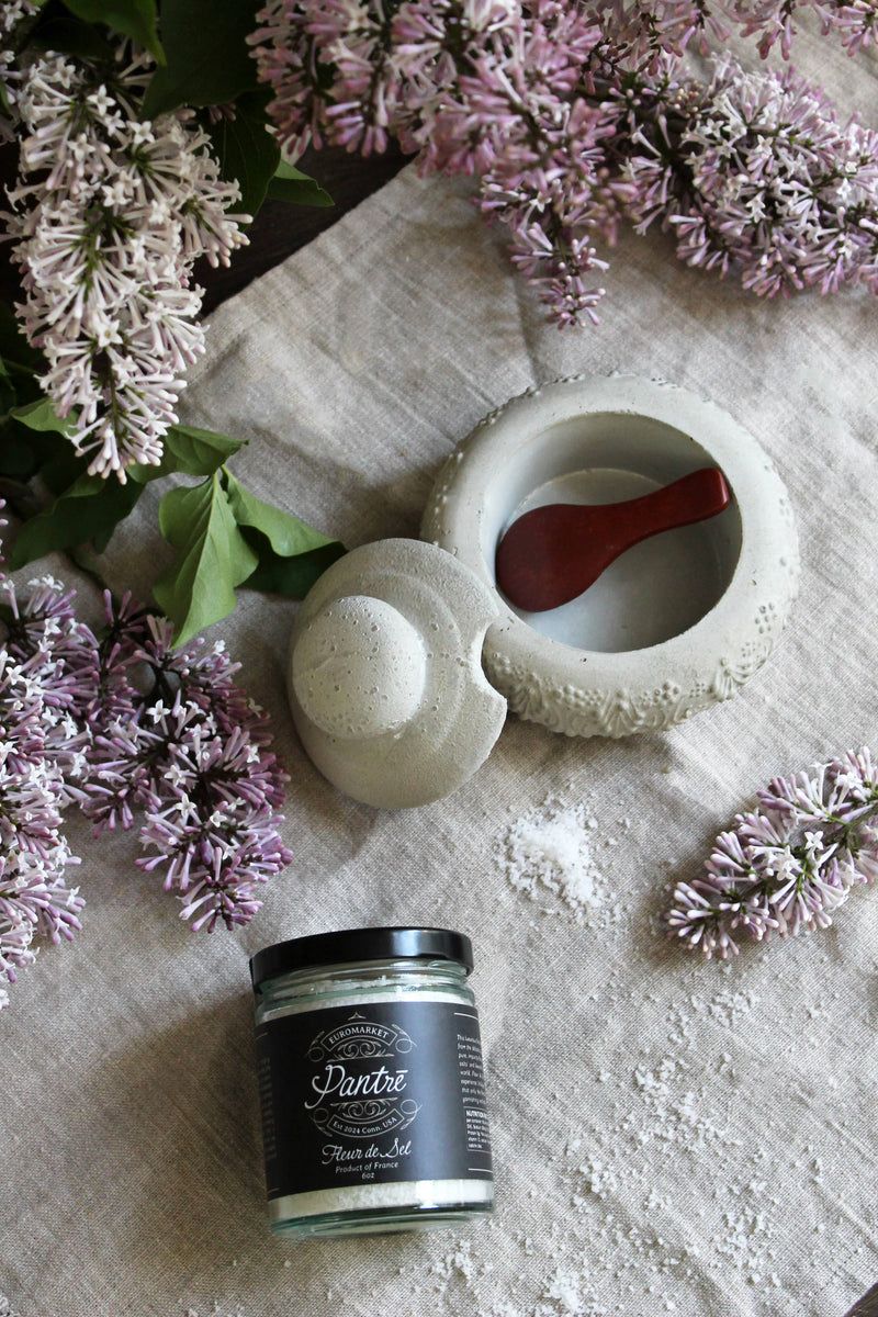 Coppermill Kitchen LLC - Vintage Inspired French Salt Cellar with wooden spoon, displayed with Pantré Fleur de Sel, lilac sprigs, and coarse salt on linen.