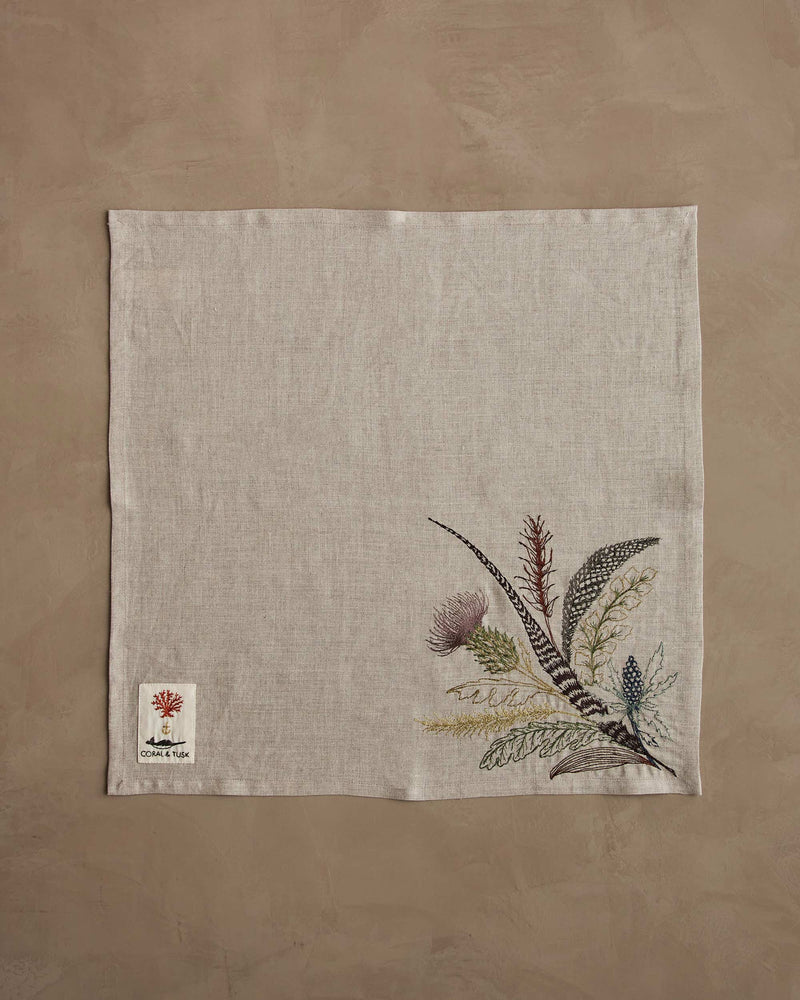 Coral & Tusk - Thistle Dinner Napkin featuring embroidered thistles, greenery, and feathers. A natural-linen piece perfect for adding an elegant, seasonal touch to your table setting.