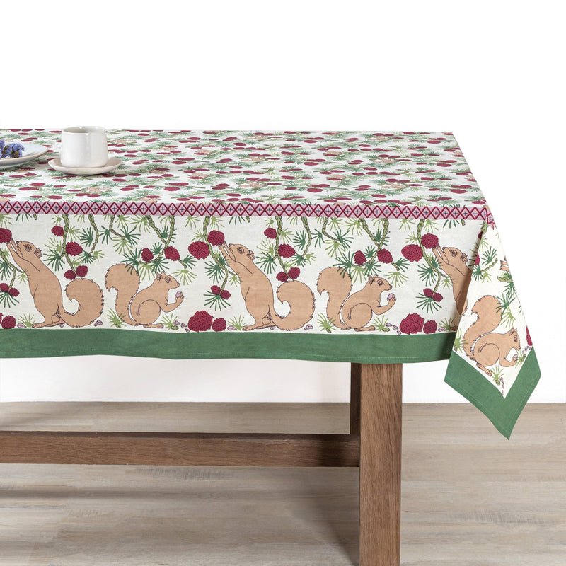 Couleur Nature - Squirrel and Pinecone Red & Brown Tablecloth: 71 x 71 on a wooden table, adorned with a white mug and plate with purple flowers.