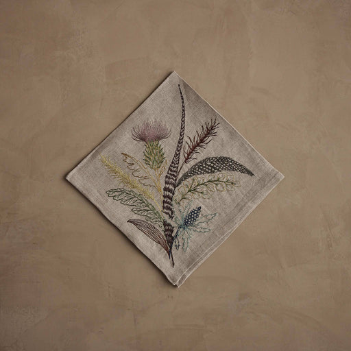 Coral & Tusk - Thistle Dinner Napkin featuring embroidered thistle, greenery, and feathers in muted tones on natural linen, perfect for seasonal table decor. Measures 20 × 20.