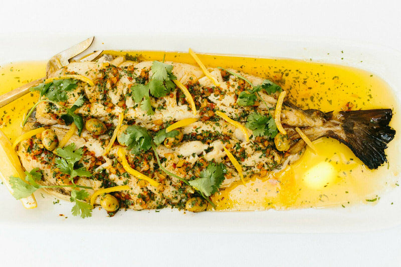 Villa Jerada - Picholine Olives enhance a roasted white-fleshed fish, adorned with herbs, garlic, lemon zest, and olives in a citrus-olive oil sauce.