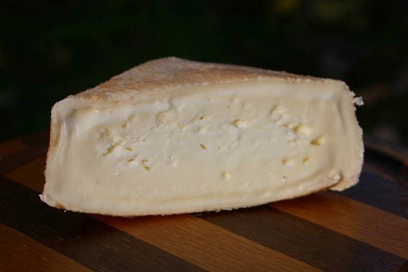 Tulip Tree Creamery - Foxglove cheese on a wooden surface, showcasing its washed rind and soft, runny texture, an award-winning specialty food available at Athens Cooks.