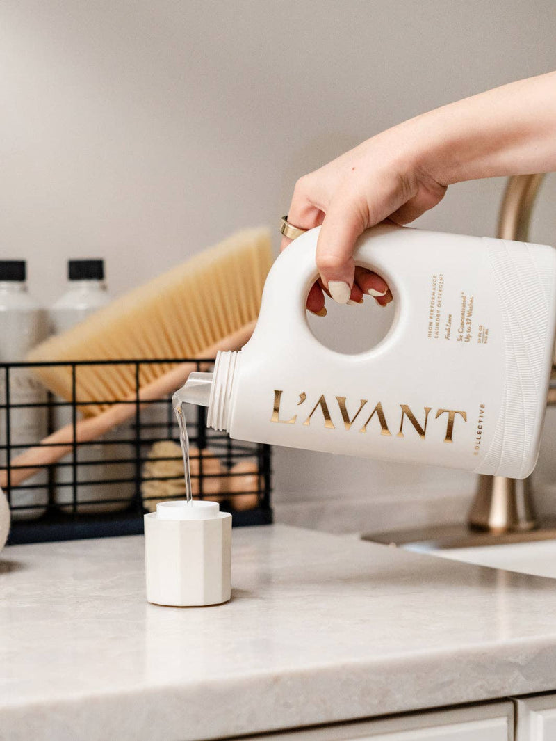 L’AVANT Collective - Laundry Detergent Fresh Linen being poured into a dosing cup, highlighting its eco-friendly, enzyme-driven formula for effective, gentle fabric care.