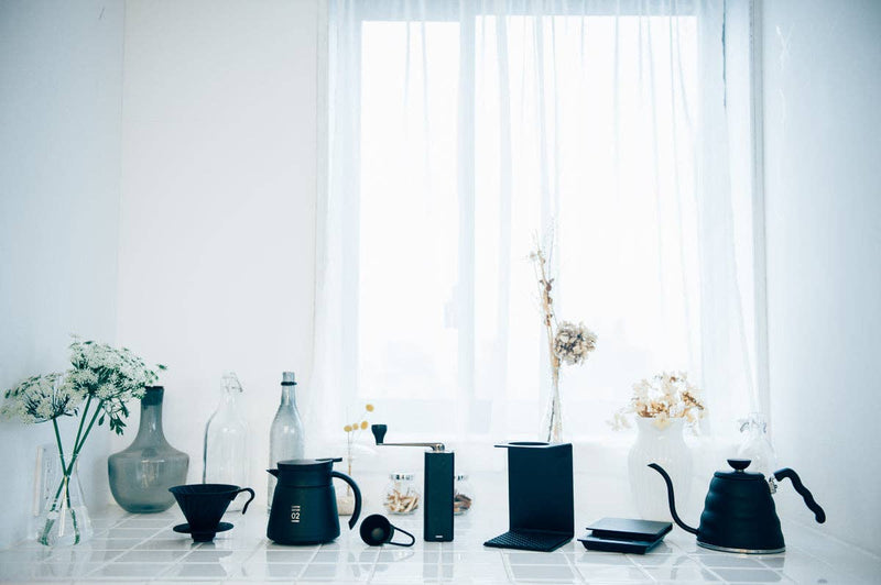 V60 Metal Dripper on a sunlit countertop, surrounded by coffee tools, epitomizing precision brewing for rich, aromatic coffee at Athens Cooks.