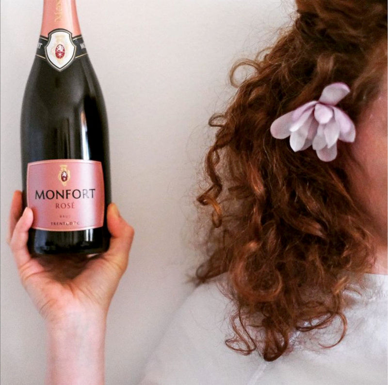 Woman holding Monfort | Brut Rosé Trentodoc wine bottle, showcasing its elegant design, reflective of traditional Italian winemaking by Cantine Monfort in Trentino.