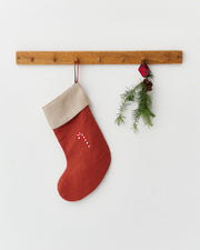 MagicLinen | Candy Cane Embroidered Christmas Stocking, crafted from sustainable linen, hangs on a peg rail, complete with a festive candy-cane motif and evergreen sprig.