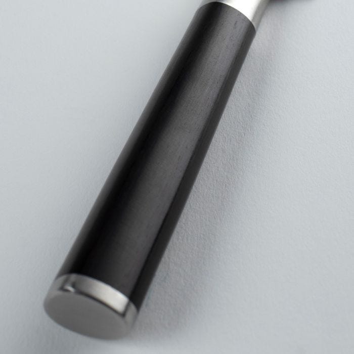 Close-up of the Shun Classic Chef's Ebony 6-inch knife handle, featuring a black cylindrical wooden grip with metal ferrules, highlighting its ergonomic, lightweight design.