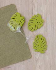 Merino Wool Monstera Coaster set of 4, featuring felt leaves beside a wine glass, ideal for stylish table settings.