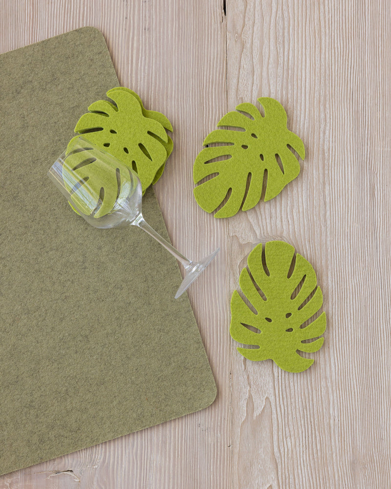 Merino Wool Monstera Coaster set of 4, featuring felt leaves beside a wine glass, ideal for stylish table settings.