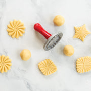 Nordic Ware | Pretty Pleated Cookie Stamps with dough and stamped cookies, showcasing star, diamond, and floral 3D imprints.