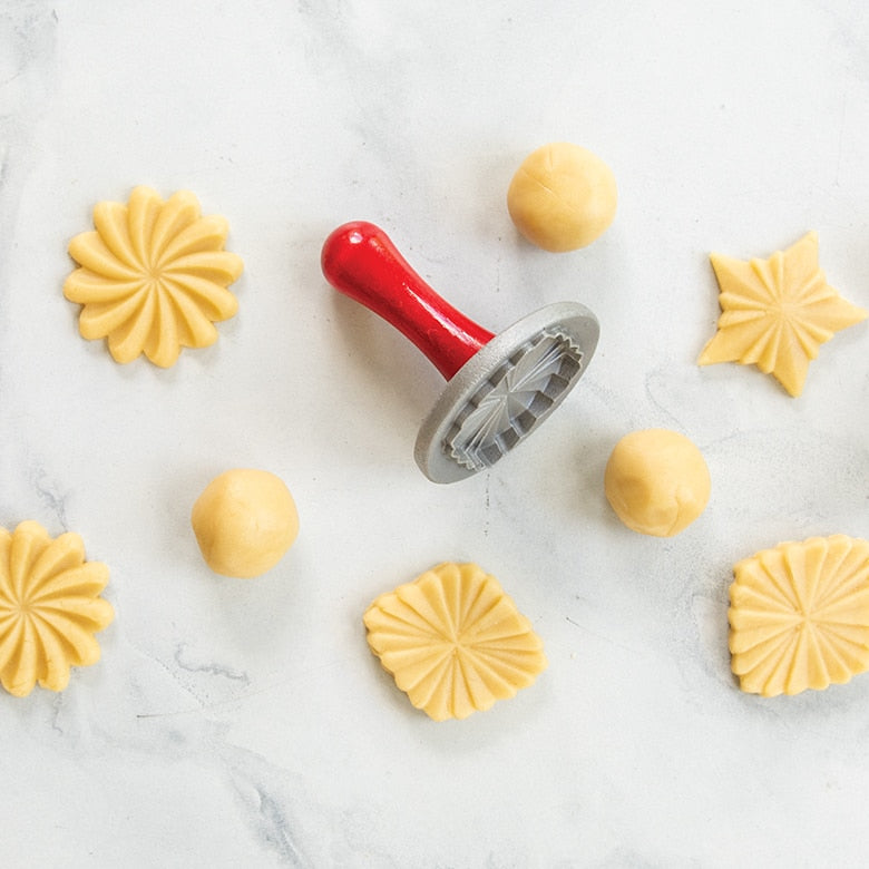Nordic Ware | Pretty Pleated Cookie Stamps with dough and stamped cookies, showcasing star, diamond, and floral 3D imprints.