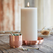 The Floral Society | Match Strike and Holder, a handmade copper vessel with textured surface, sits on a rustic table alongside a lit candle and spent matches.