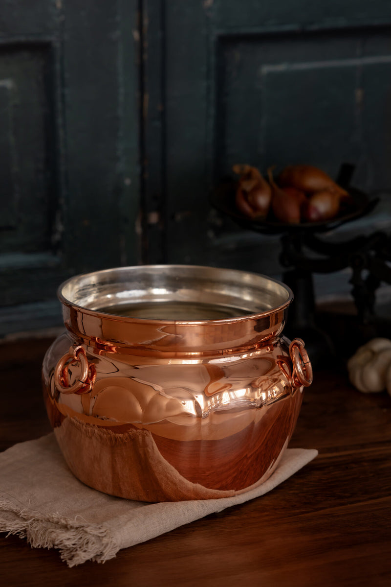 Coppermill Kitchen LLC | Vintage Inspired Copper Pot on linen cloth, ideal for stews, with side rings and tin lining, reflecting timeless culinary craftsmanship.