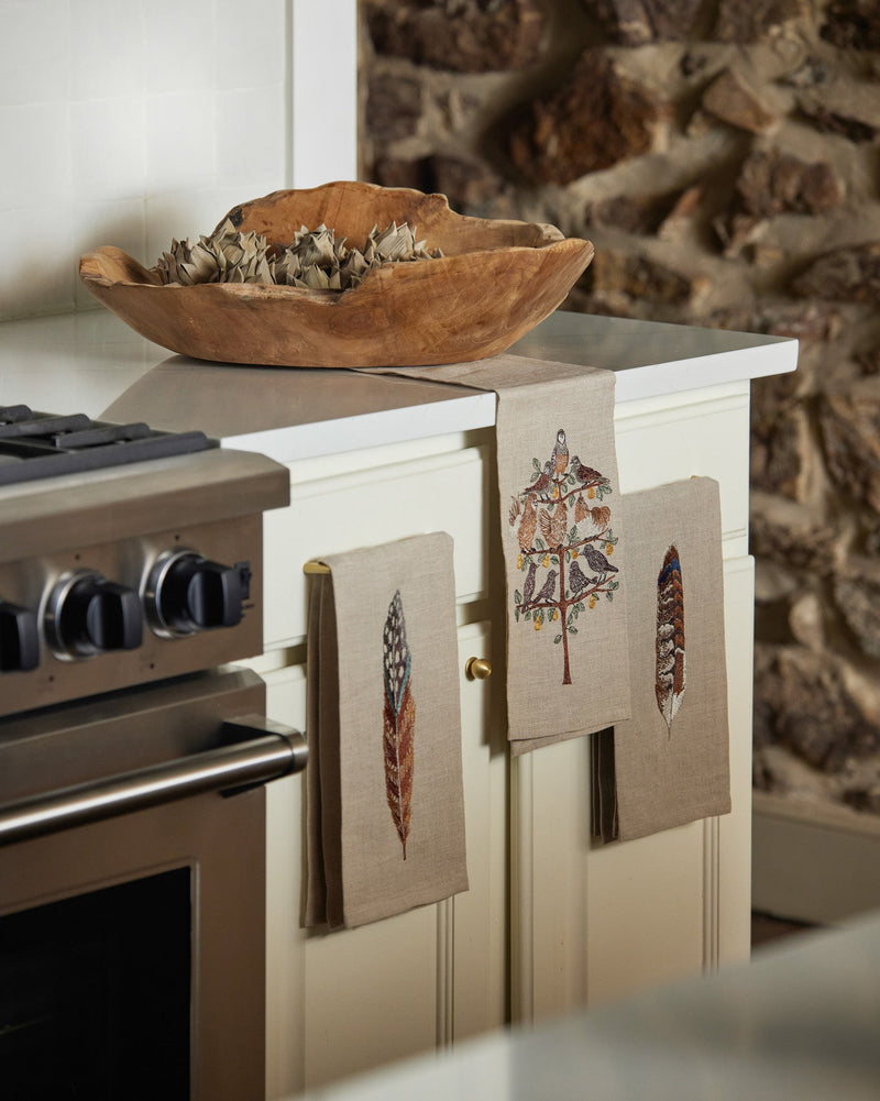 Partridge in a Pear Tree Tea Towel with embroidered tree and birds, displayed on a kitchen cabinet in Athens Cooks' curated kitchen setting.