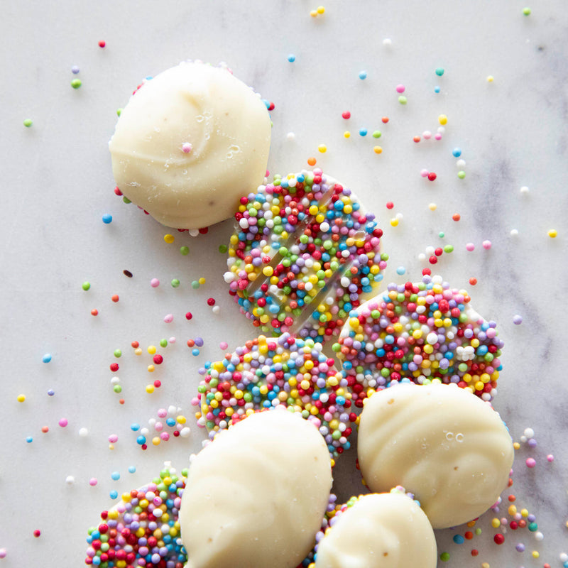 Hester & Cook | Buttons - White Chocolate: Round white-chocolate nonpareils topped with colorful sprinkles on marble, perfect for snacking or gifting from Athens Cooks.