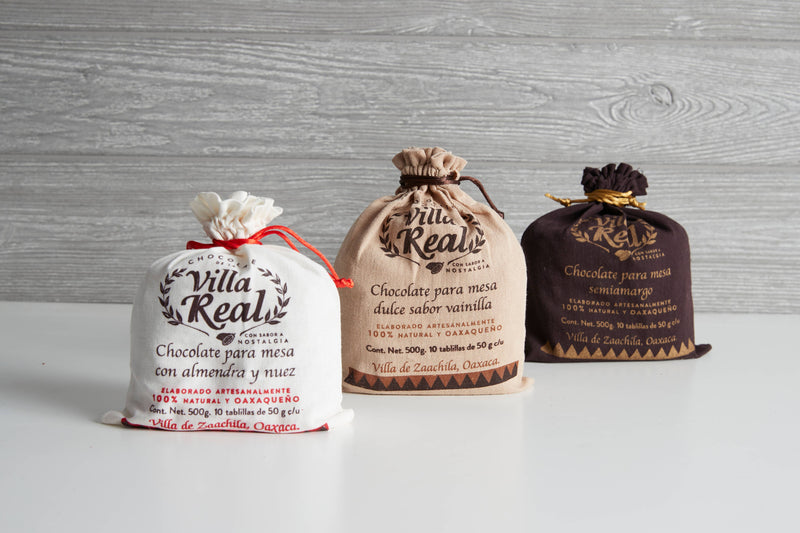 Three Villa Real draw-string pouches: almond & walnut, vanilla, and semi-bitter flavors, each containing 500g of Oaxacan artisanal table chocolate tablets.