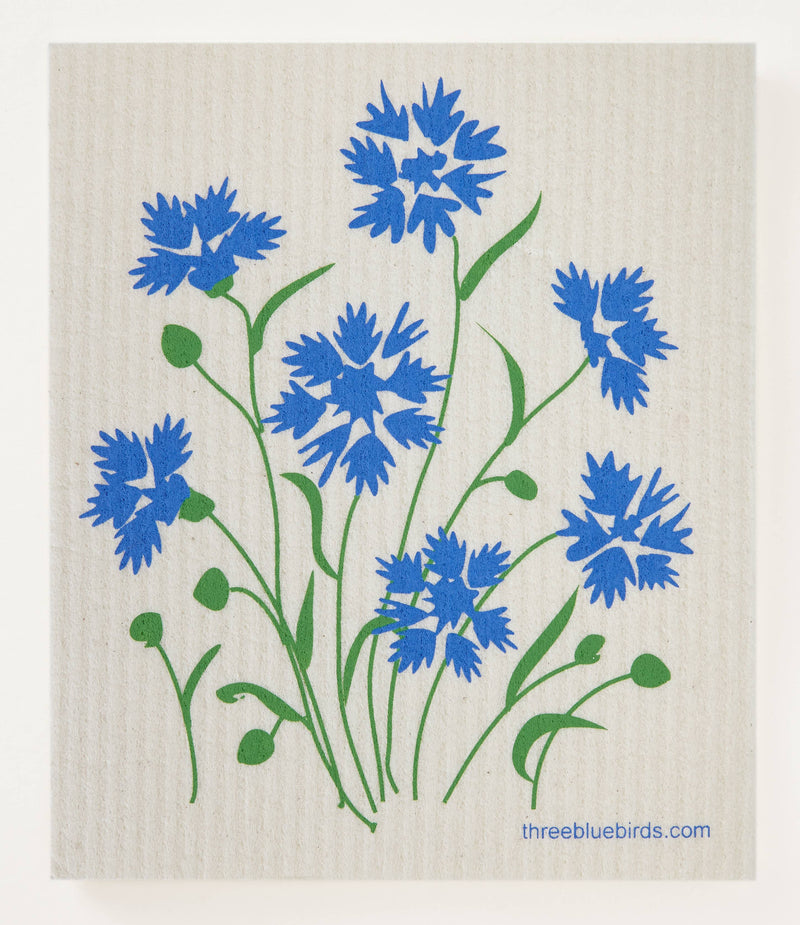 Three Bluebirds Swedish Dishcloths - Cornflowers showcased with blue flowers and green leaves on a white surface, highlighting its eco-friendly and absorbent features.