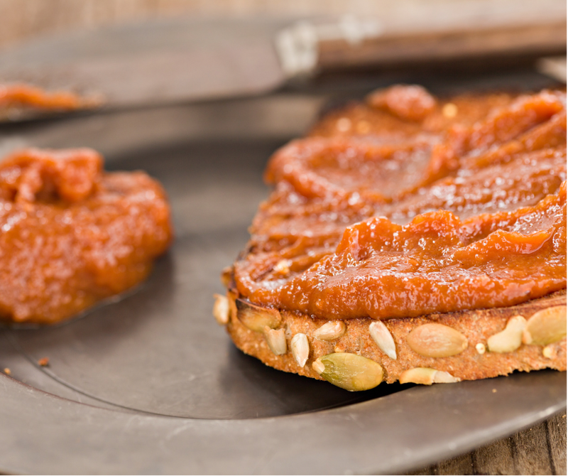 Southern Roots Sisters - Maple Pumpkin Butter spread on multigrain bread slice with background knife and extra spread, highlighting its rich, buttery texture and autumn flavors.
