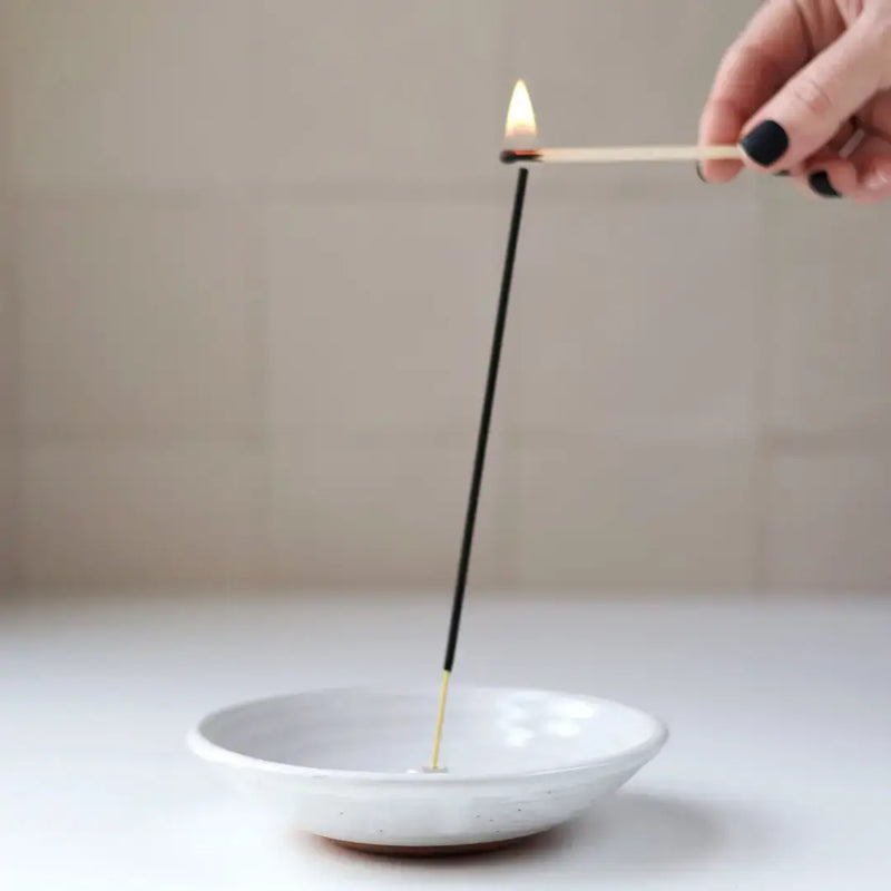 Gravesco Pottery - Incense Burner in 4 colors; a hand lights incense over a white ceramic dish, ideal for catching ash and easy cleaning.