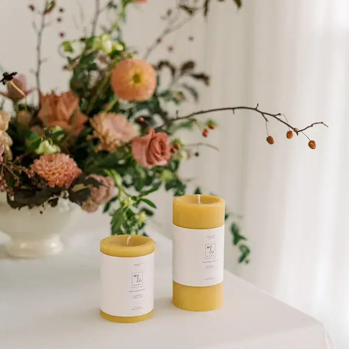 Mo&Co Home - 100% Beeswax Pillar Candles in a cozy setup with a white vase of peachy blooms, perfect for elegant home decor.