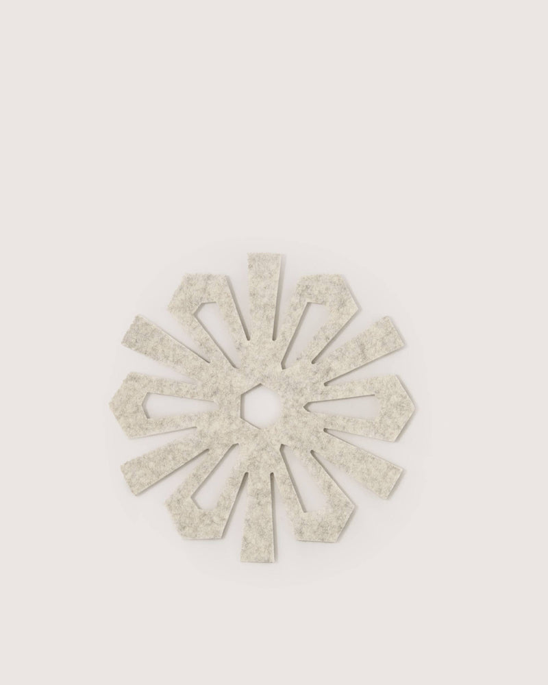 Graf Lantz - Merino Wool Snowflake Trivet - Heather White, featuring a radial starburst design in light-beige felt, perfect for adding elegance and protection to holiday gatherings.