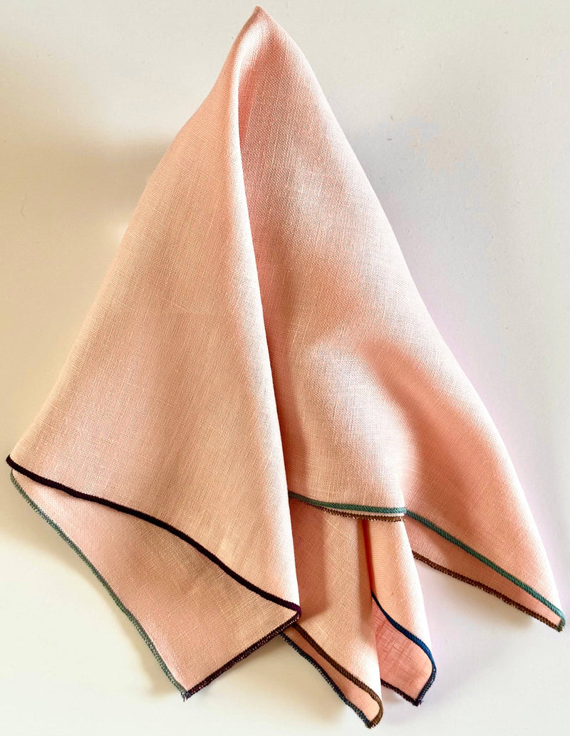 Tisch New York - Napkins, Blush Linen (Night Fall Hem), featuring a peach-pink linen square with colorful serged edges, sold in sets of four.