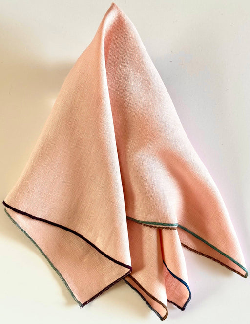 Tisch New York - Napkins, Blush Linen (Night Fall Hem), featuring a peach-pink linen square with colorful serged edges, sold in sets of four.
