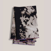 ATELIER SAUCIER - Sundown Linen Napkins: Set of 4 black-and-off-white tie-dyed cloth napkins with multicolored trim, perfect for enhancing elegant table settings.