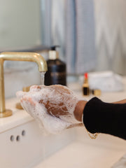 L'AVANT Collective - Fresh Linen Hand Soap being used, featuring a luxurious matte black glass bottle at a sink, enhancing the eco-luxe handwashing experience.