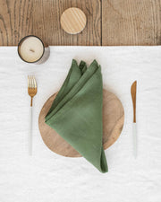 MagicLinen - Set of 2 linen napkins on a wooden plate with a candle, showcasing their elegant, versatile table decor design.