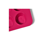Great Jones | Stud Muffin - Blueberry: Close-up of a pink, nonstick pan designed for baking 12 muffins, featuring even heat distribution and easy cleanup.