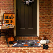 Carolina Creekhouse Boo-Tiful FloorFlat, a whimsical 2'x3' Halloween-themed mat, features ghosts, spiderwebs, and pumpkins, complementing a festive porch with pumpkins and decorative accents.