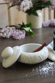 Coppermill Kitchen LLC - Vintage Inspired French Salt Cellar with textured ceramic finish, matching lid, and included wooden spoon on a wooden tabletop with scattered salt.