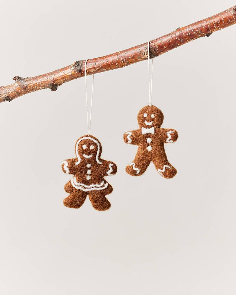 Farmhouse Pottery - Felted Gingerbread Ornament: Lady, handcrafted from 100% wool, features white icing details and a skirt-like ruffle, hanging from a tree branch.