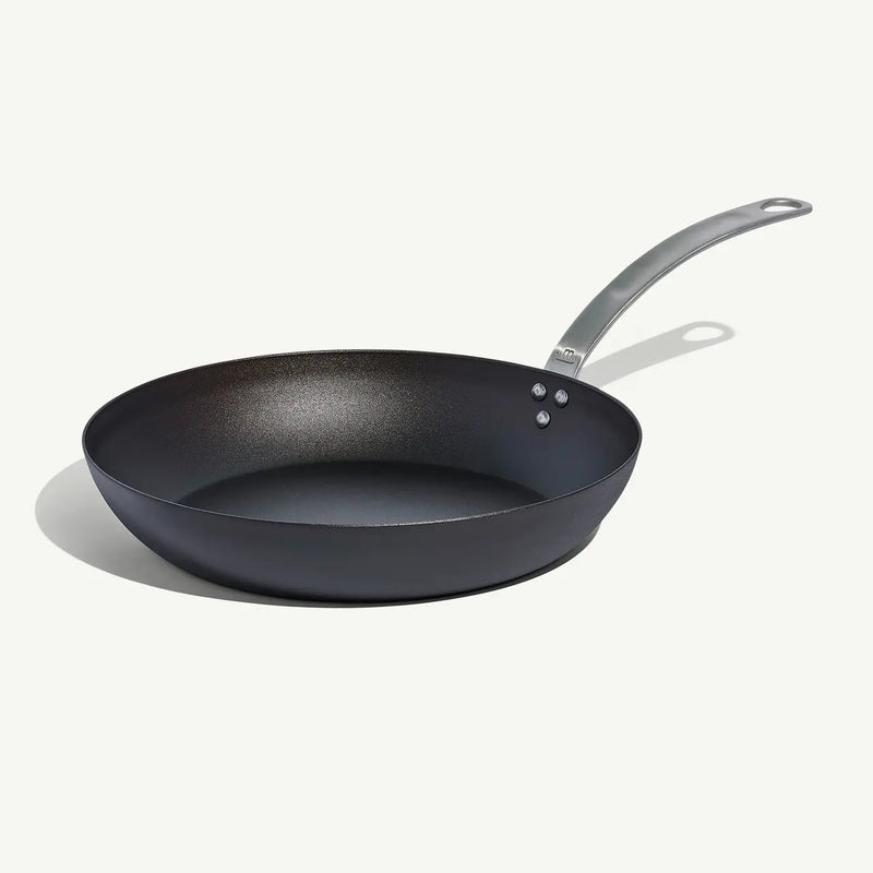 Made In | Carbon Steel Frying Pan, 12-inch, features a black non-stick surface and stainless-steel handle, ideal for high-heat searing and versatile cooking.