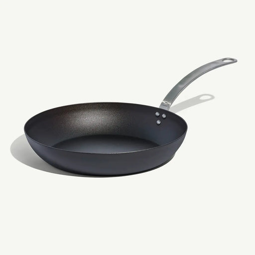 Made In | Carbon Steel Frying Pan, 12-inch, features a black non-stick surface and stainless-steel handle, ideal for high-heat searing and versatile cooking.