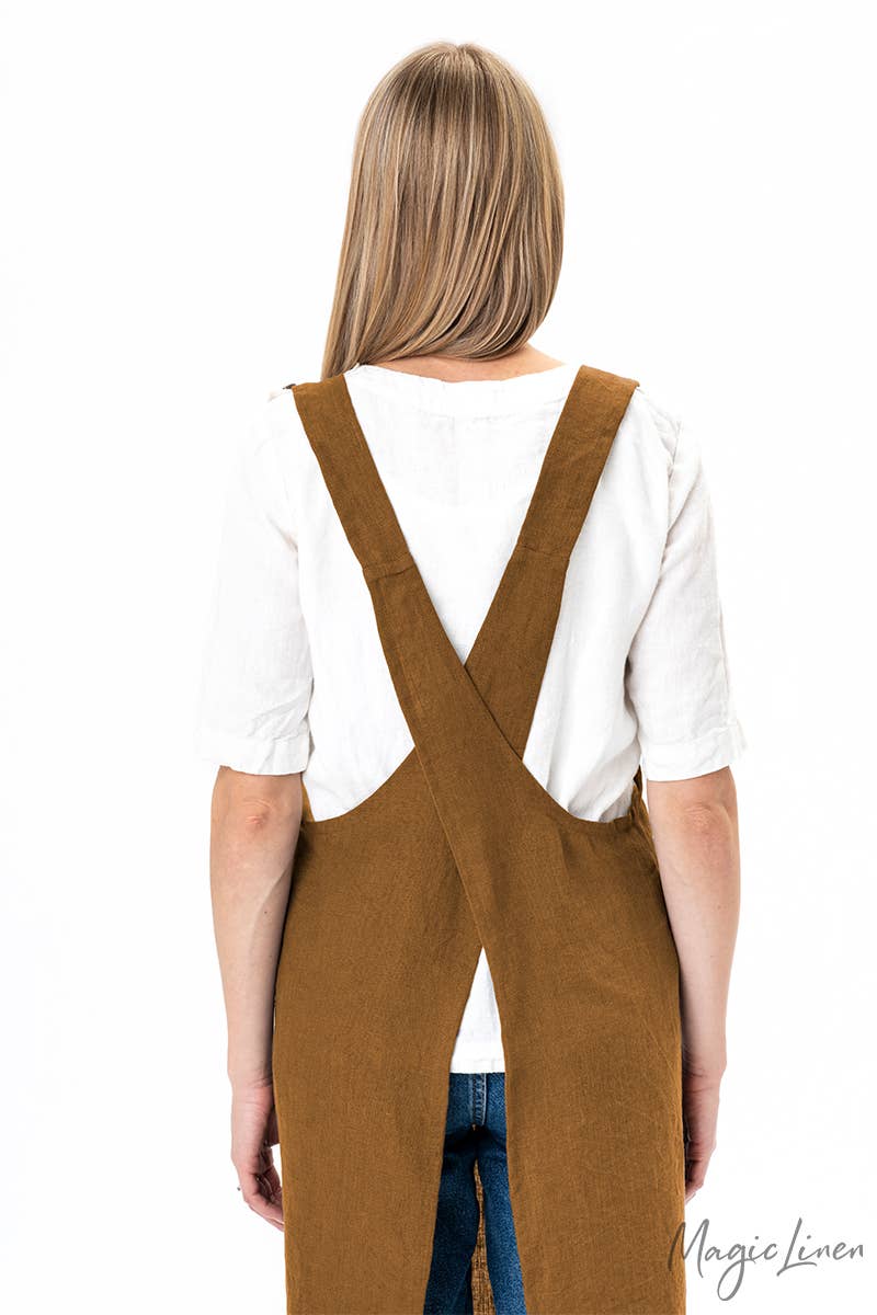 Woman wearing MagicLinen's pinafore cross-back linen apron with front pocket, ideal for cooking and gardening, highlighting its durable and stylish design.