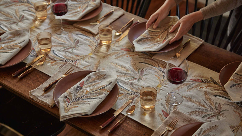 Coral & Tusk - Wheat Harvest Dinner Napkin elegantly set on a wooden dining table, showcasing autumnal warmth with coordinating table runner and gold-tone flatware.