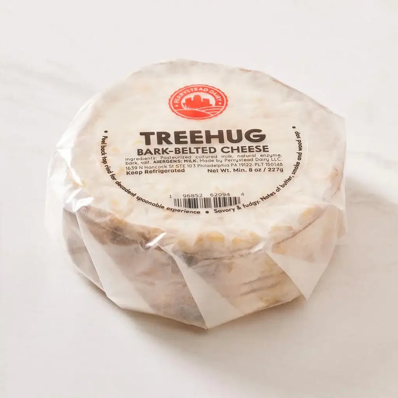 Perrystead Dairy - Treehug cheese, wrapped in plastic, features a barcode, ideal for holiday gatherings with its creamy, spoonable interior.