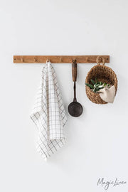 Linen tea towel hanging on a hook, accompanied by a spoon and a basket, showcasing its practicality and high-quality European craftsmanship. Ideal for kitchen use.
