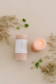 Mo&Co Home - 100% Beeswax Pillar Candles | Rose Pink: 3x4 Inch candle with a flame, accompanied by green leaves and a white paper with text.