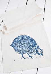 Hearth and Harrow - Organic Cotton Guinea Hen Tea Towel in Navy Blue, featuring a stylized guinea fowl design, laid on a wooden surface, ideal for kitchen use.