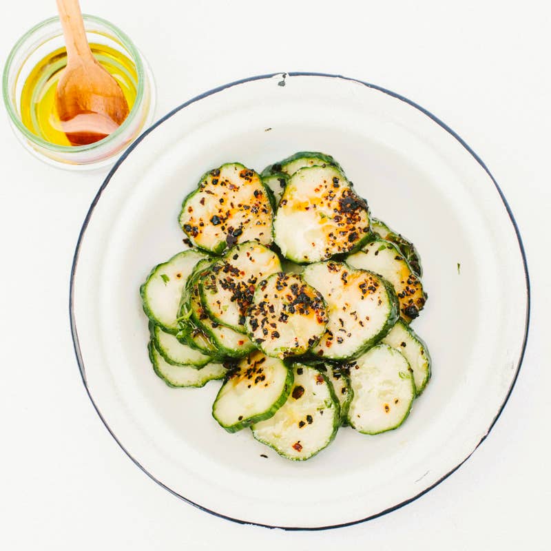 Villa Jerada - Urfa Biber - 50g pepper enhances cucumber dish with charred slices, chili flakes, herbs, and drizzled oil, embodying complex, mild, smoky flavors.