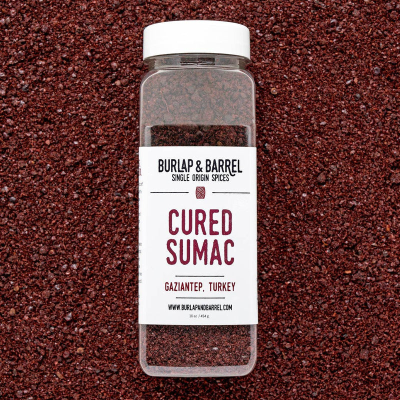 Burlap & Barrel - Cured Sumac (Sumak) - Single Origin Spice & Seasoning: 2.3 oz glass jar on deep-red spice bed, offering a bright, sour flavor.